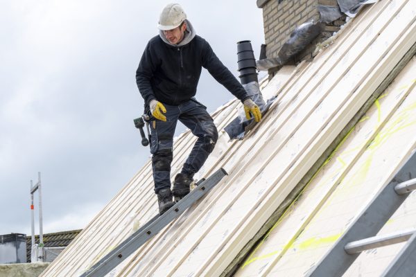 Portrait of tradesman on a roof wearing safety gear and hard hat